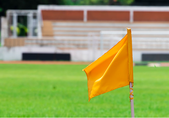 bandeira amarela de escanteio em um campo com gramado verde