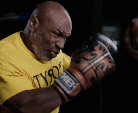 GIF de Mike Tyson usando camiseta amarela e luvas de boxe durante um treinamento
