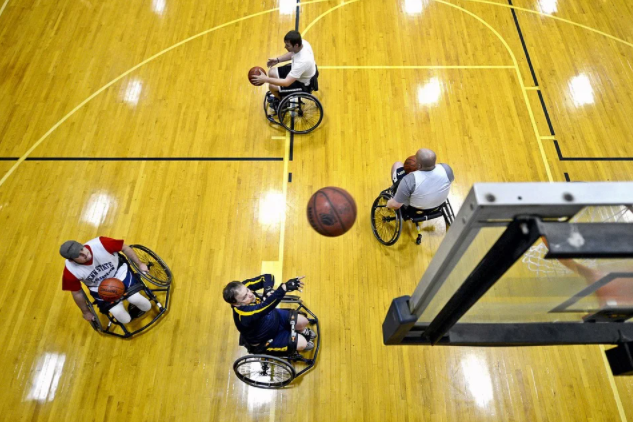 quatro jogadores paralímpicos, cada um com uma bola, treinando arremesso de basquete 